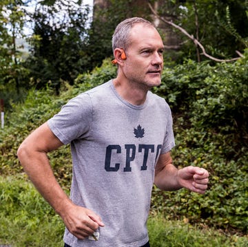 best running headphones a person running on a wooded trail in shokz openrun pro headphones