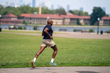 a person running in a park near a water body and buildings