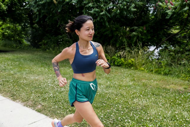 individual running along a path in a park in a sports bra