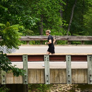 a runner passes over a bridge with a creek below it