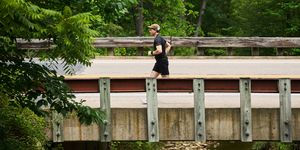 a runner passes over a bridge with a creek below it