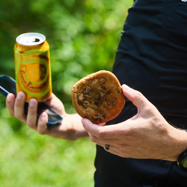 a man holding a cookie and a seltzer