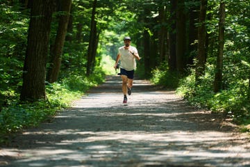 a person jogging on a dirt path surrounded by trees