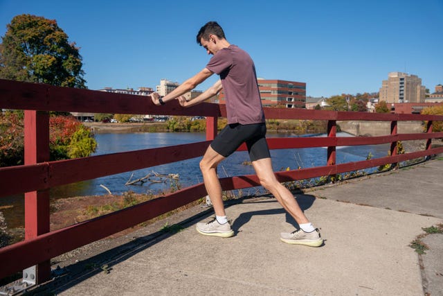 person stretching by a river with a city skyline in the background
