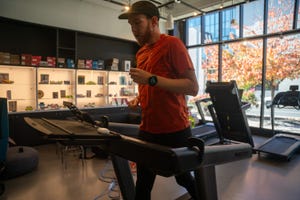 person jogging on a treadmill in a fitness area with exercise equipment in the background