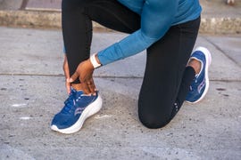 person kneeling on pavement while holding their ankle