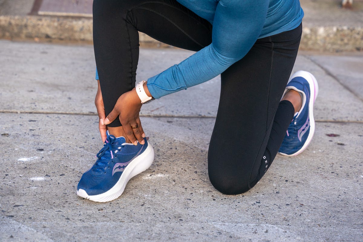 person kneeling on pavement while holding their ankle