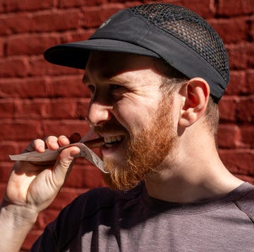person holding a device near their mouth against a red brick wall person holding a device near their mouth against a red brick wall