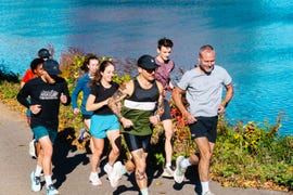 group of people jogging along a path by a body of water