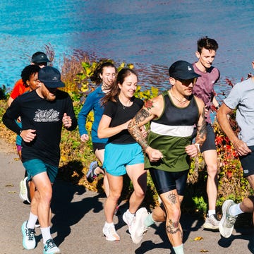 group of people jogging along a path by a body of water group of people jogging along a path by a body of water