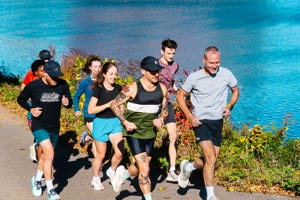 group of people jogging along a path by a body of water