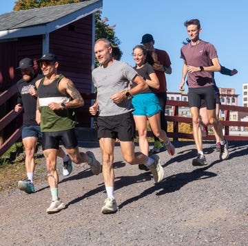 Group of runners on a gravel path with a red wooden railing and a building in the background group of runners on a gravel path with a red wooden railing and a building in the background