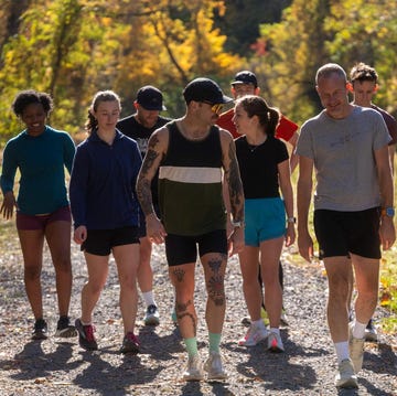group of individuals walking along a gravel path in a wooded area during autumn group of individuals walking along a gravel path in a wooded area during autumn