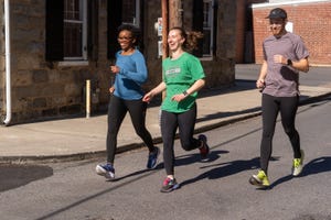 three runners jogging on a street next to a stone building