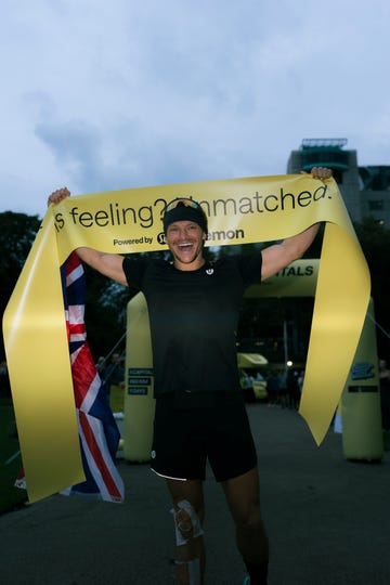 jonny davies holding up the finish line tape at the end of his run the capitals challenge