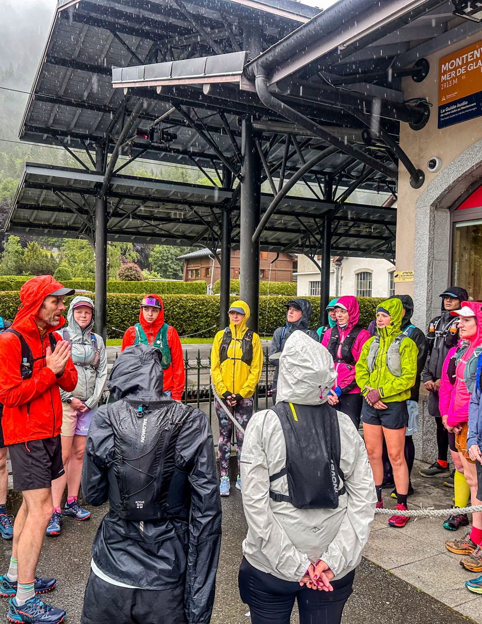 group of trail runners listen to a talk in the rain