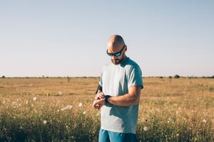 runner adjusting his smartwatch before his morning workout in the countryside