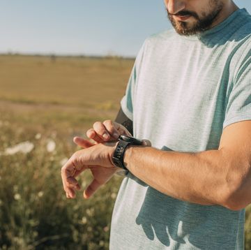 runner adjusting his smartwatch before his morning workout in the countryside