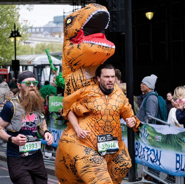 a runner in a dinosaur costume takes part during the