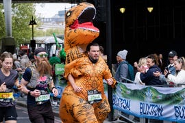 a runner in a dinosaur costume takes part during the