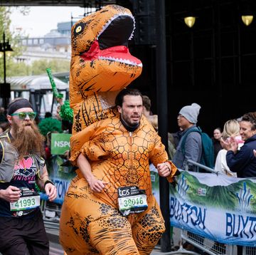 a runner in a dinosaur costume takes part during the