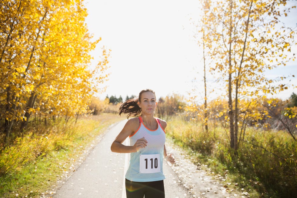 Runner racing on sunny autumn path