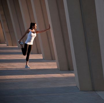 Runner stretching on concrete pillar
