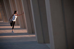 Runner stretching on concrete pillar