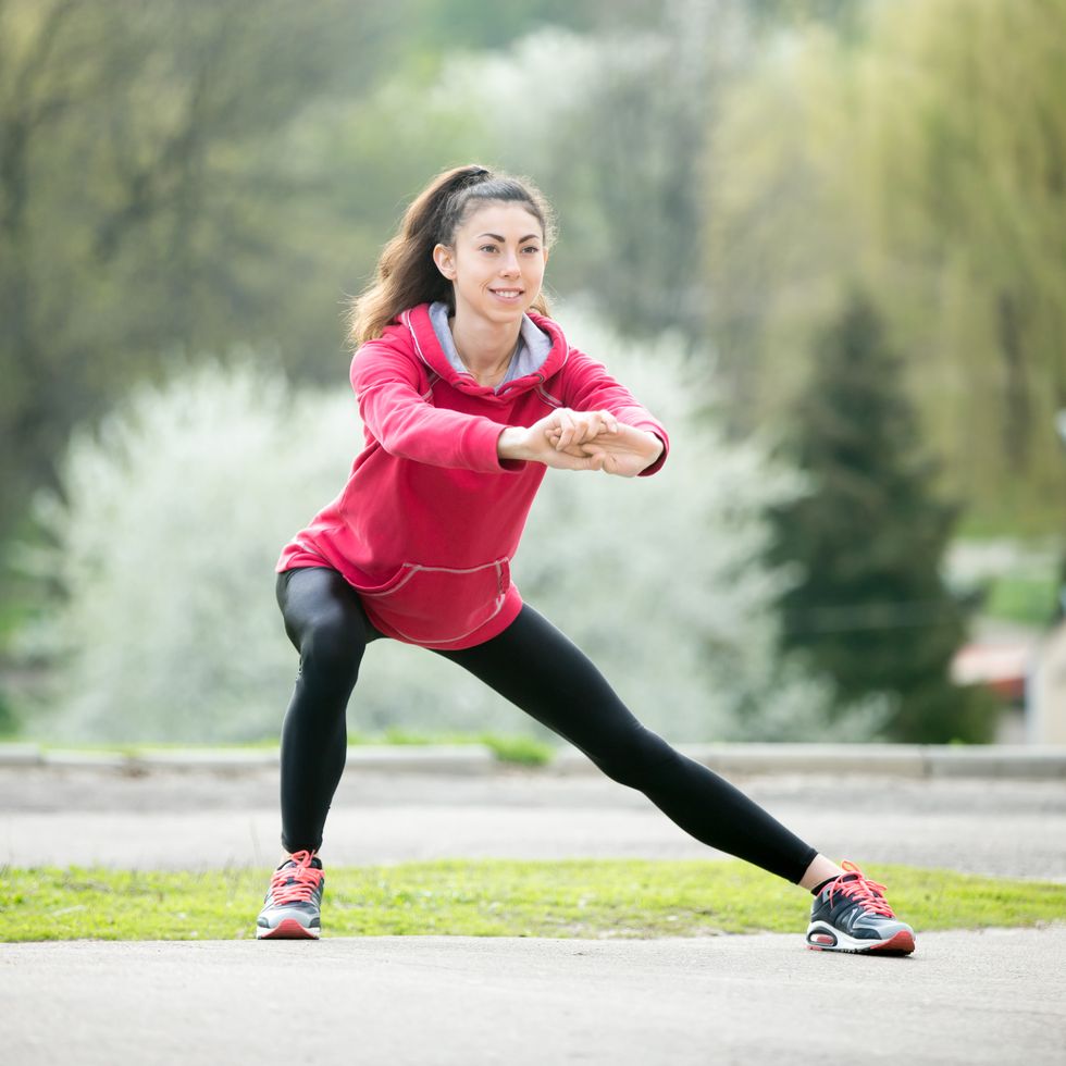 Runner woman doing side lunges before jogging