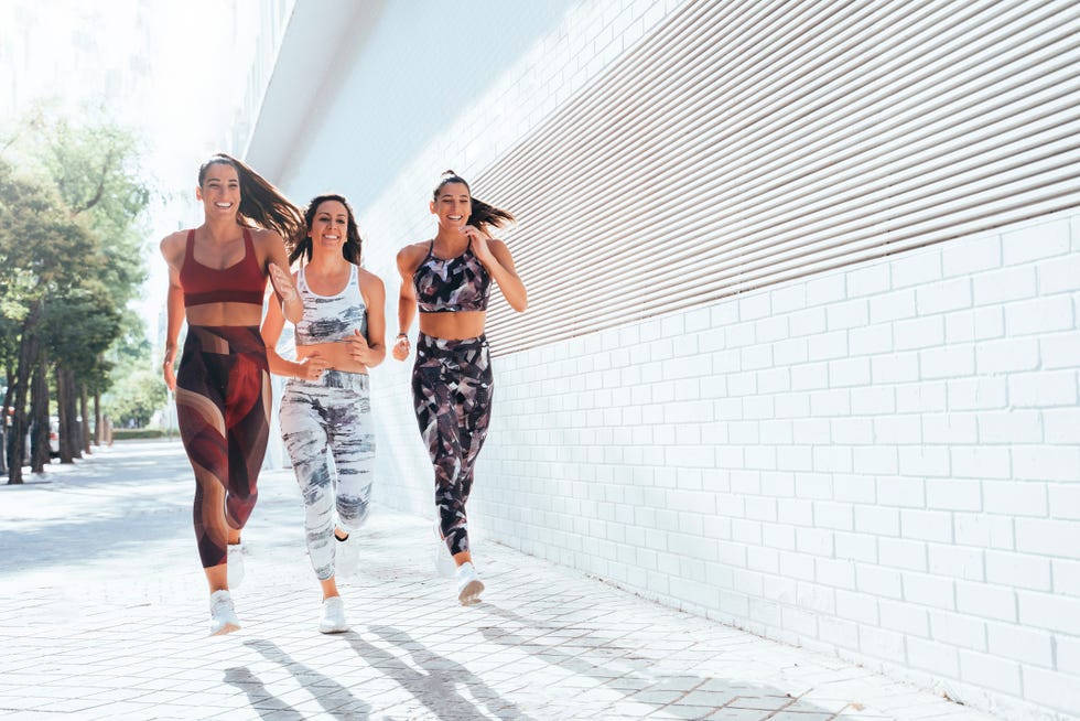 Rear view of three sporty young women running in the city