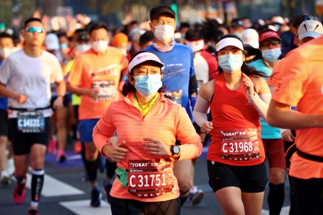 varios corredores corren el maratón de shanghái con una mascarilla puesta