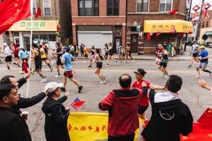 a group of runners in a race pass spectators on a city street