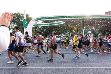 Participants in a marathon running under a colorful arch with bubbles in the air