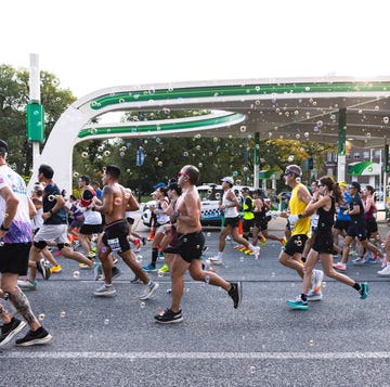 Participants in a marathon running under a colorful arch with bubbles in the air Participants in a marathon running under a colorful arch with bubbles in the air