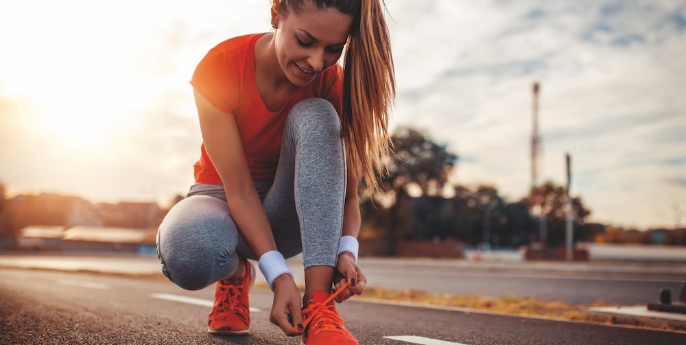female runner tying her shoes and preparing for a jogging