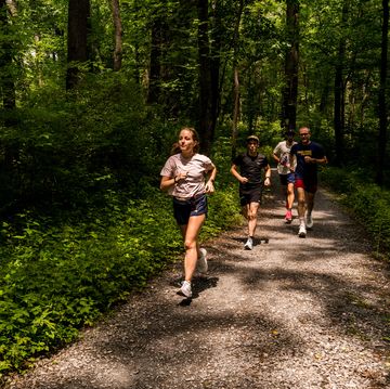 a group of people running on a trail in the woods