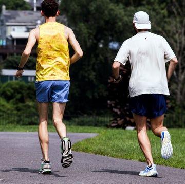 RWD two runners jogging on a path surrounded by greenery and buildings in the background