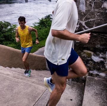 two runners go up a set of stairs with a river in the background