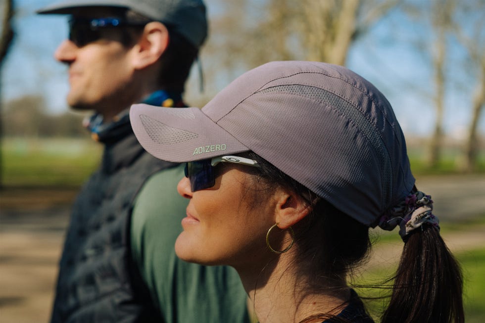 two people looking off to the distance, the woman is wearing a purple running cap with her hair tied in a pony tail