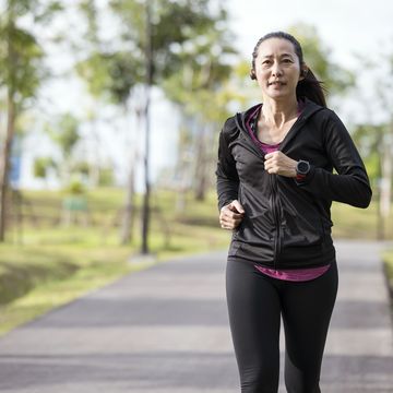 running for exercise "slows the aging process". an asian woman running exercises in an urban park outdoors.