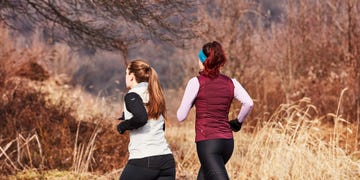 two women running through some frosty woodland wearing running gilets and long sleeves
