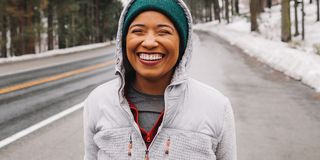 runner smiling in green hat on side of snowy road