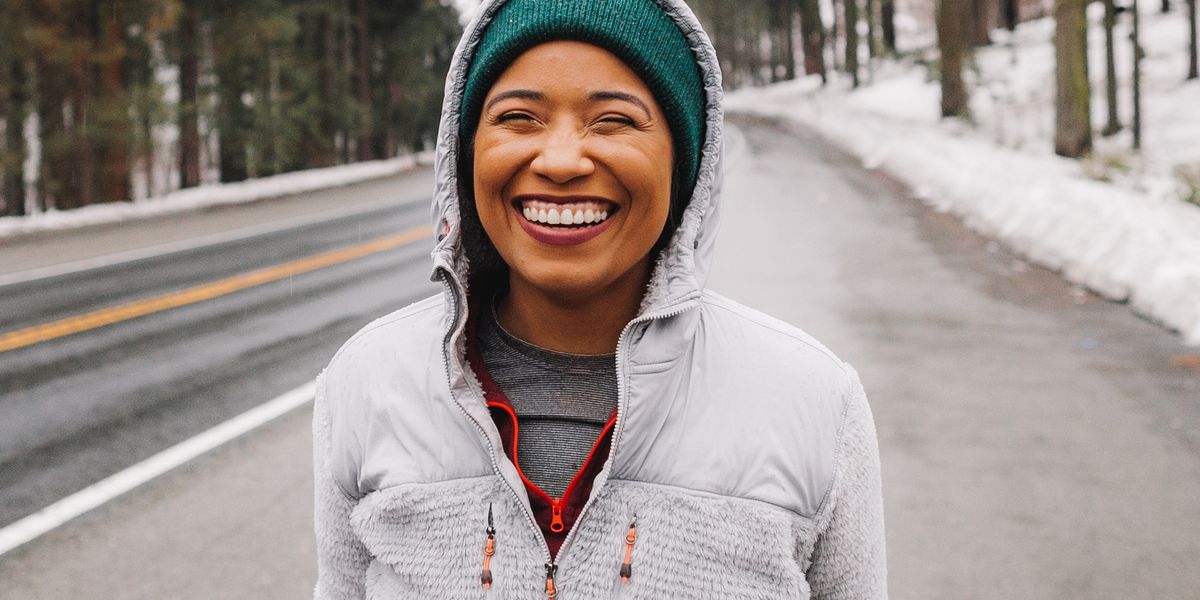 runner smiling in green hat on side of snowy road