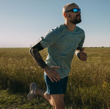 running in the countryside: fit man in blue sportswear during his outdoor cardio workout in nature