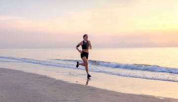 person running along a beach at sunrise