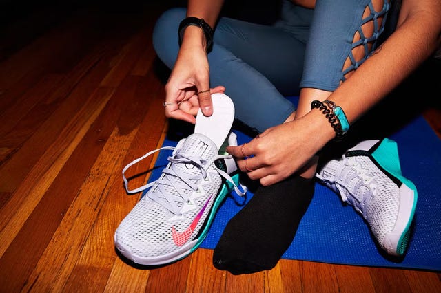 woman putting an insole in her running shoes