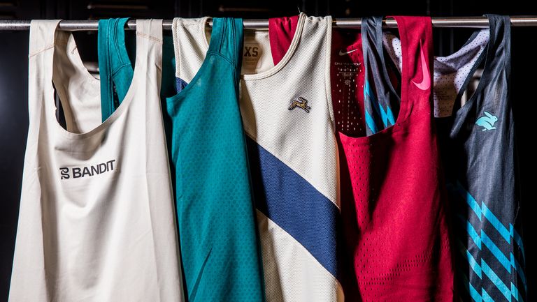 a group of running singlets hanging on a rolling rack