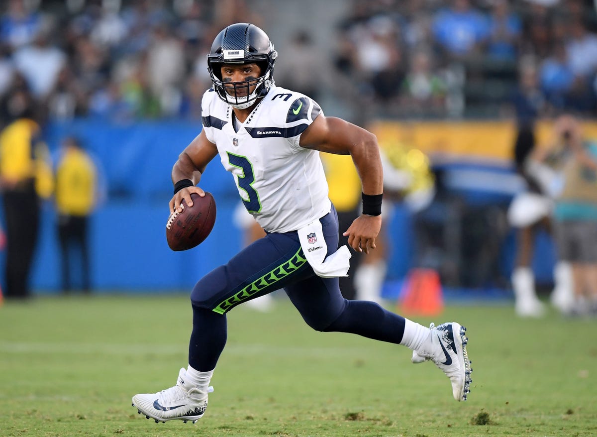 Seattle hip hop and rap singer Macklemore greets Seattle Seahawks  quarterback Russell Wilson before an NFL football game between the Seahawks  and Tennessee Titans, Sunday, Oct. 13, 2013, in Seattle. (AP Photo/Elaine