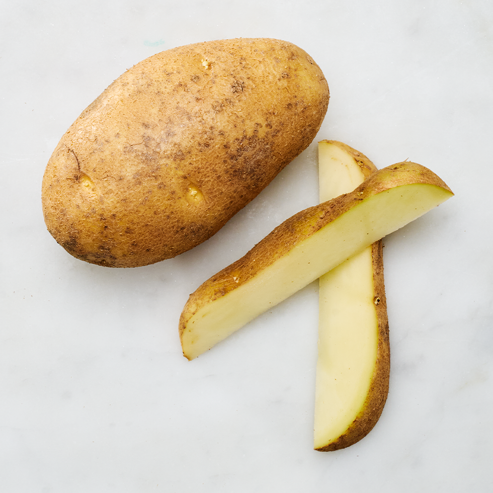 raw russet potato with a slice cut out revealing its white interior