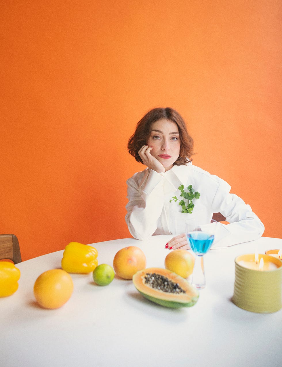 lourdes hernández con vestido de sportmax, ante una mesa con velas de madreselva y azahar de loewe perfumes y copa de mestizo store